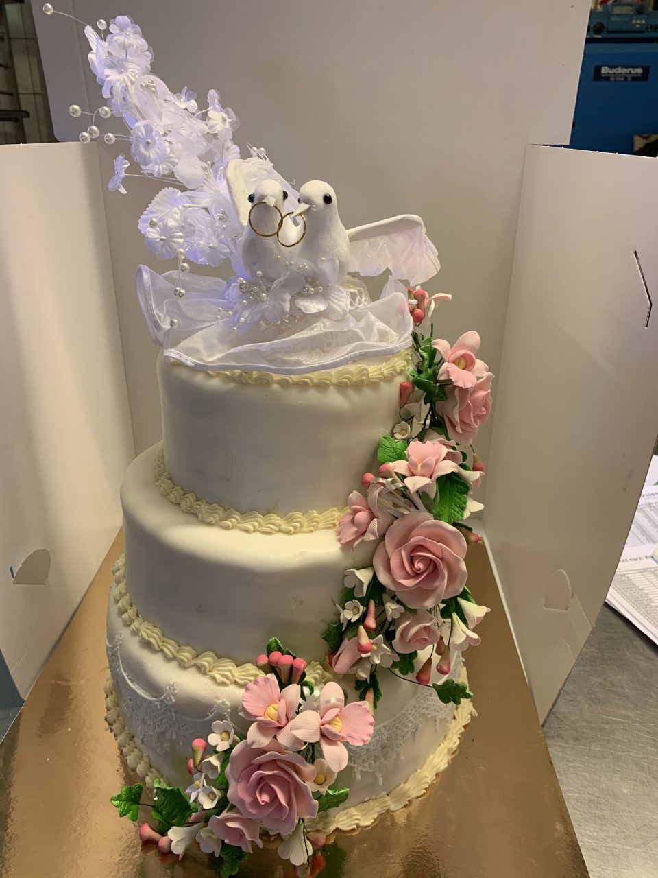 Mehrstöckige weiße Hochzeitstorte mit Blumenverzierung und Tauben