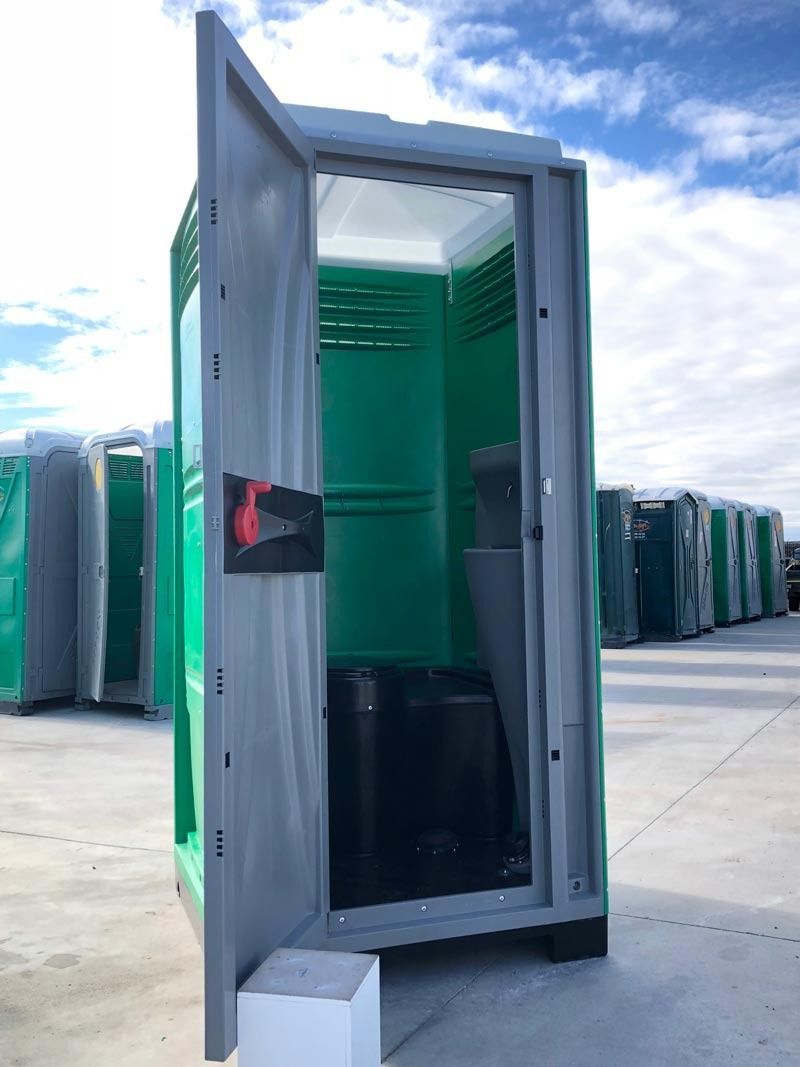Un baño portátil verde y gris con la puerta abierta.