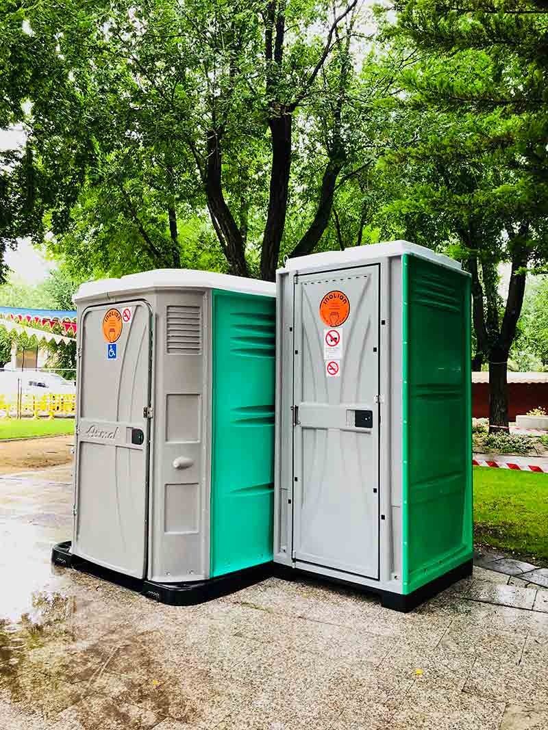 Hay dos baños portátiles uno al lado del otro en un parque.