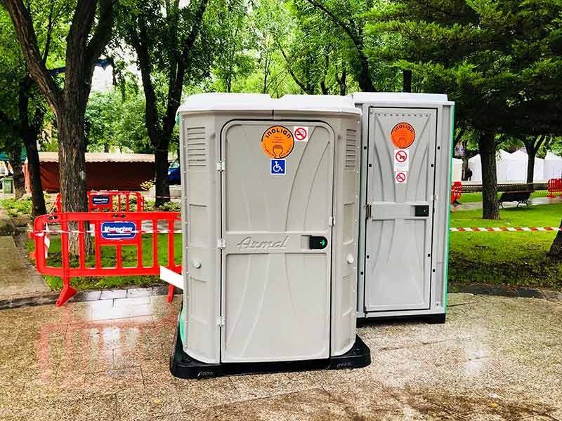 Hay dos baños portátiles uno al lado del otro en un parque.