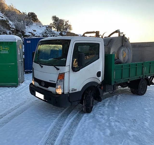 Un camión blanco con una caja verde está estacionado en la nieve.