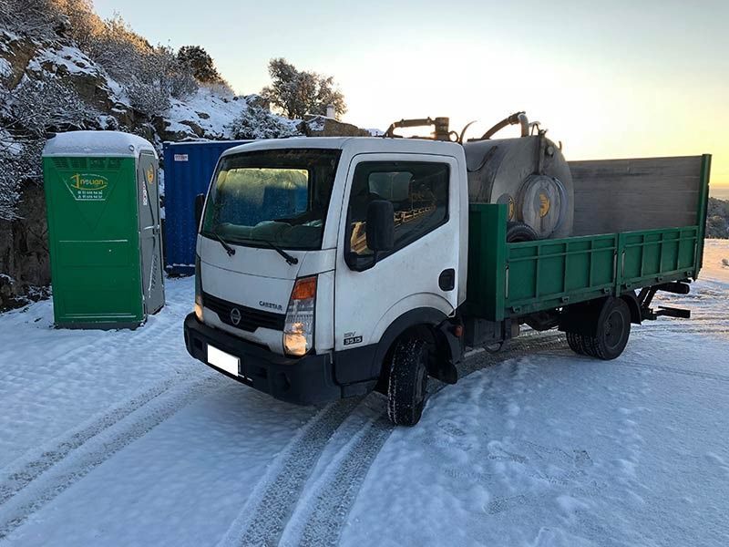 Un camión blanco con una caja verde está estacionado en la nieve.
