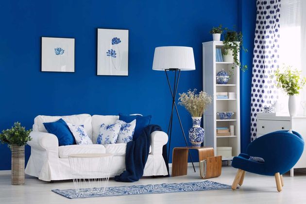 Una sala de estar con paredes azules y un sofá blanco.