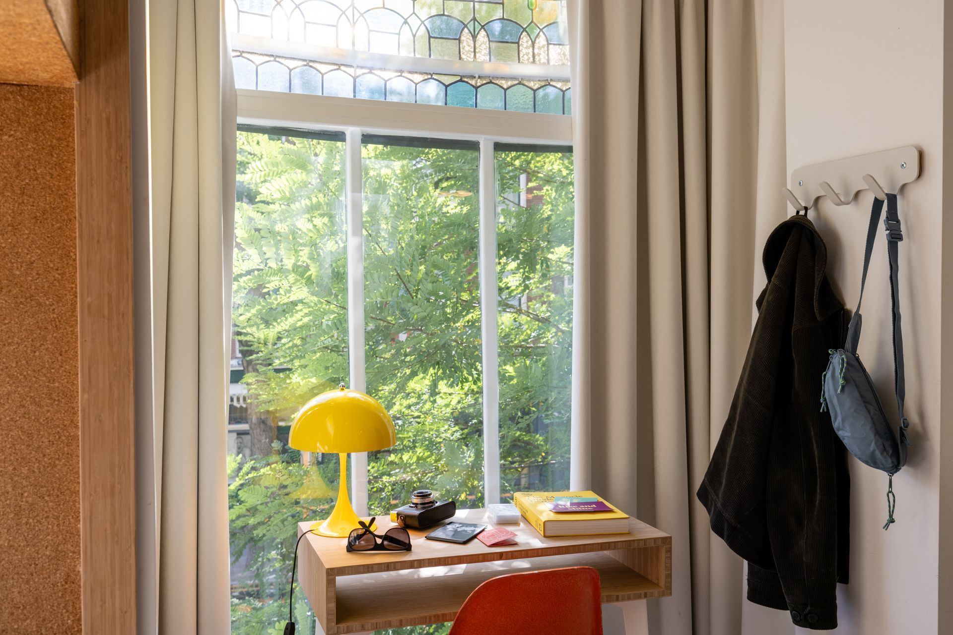 A room with a desk , chair , lamp and window.