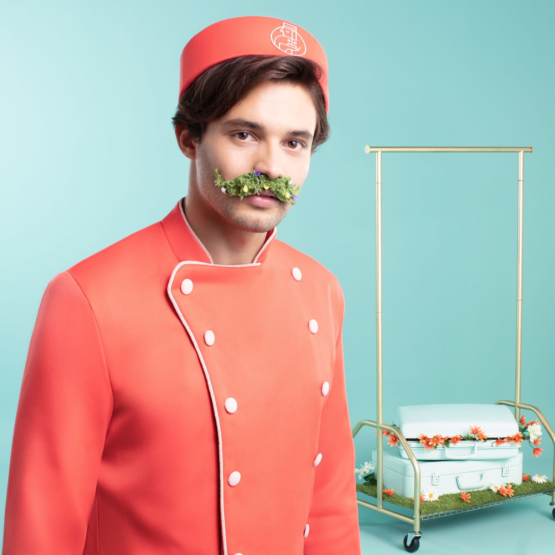 A man in a chef 's uniform has a mustache made of lettuce