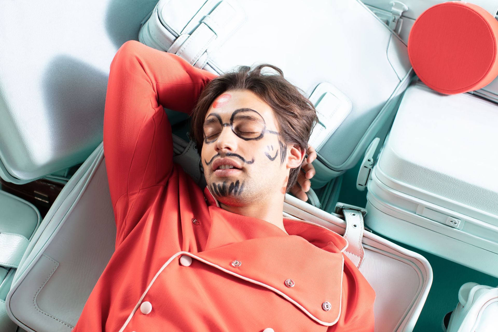 A man is laying on top of a pile of suitcases.