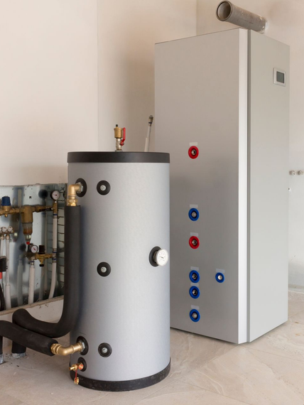 Chaufferie avec réservoir d'eau chaude blanc, armoire utilitaire haute et tuyaux apparents contre un mur