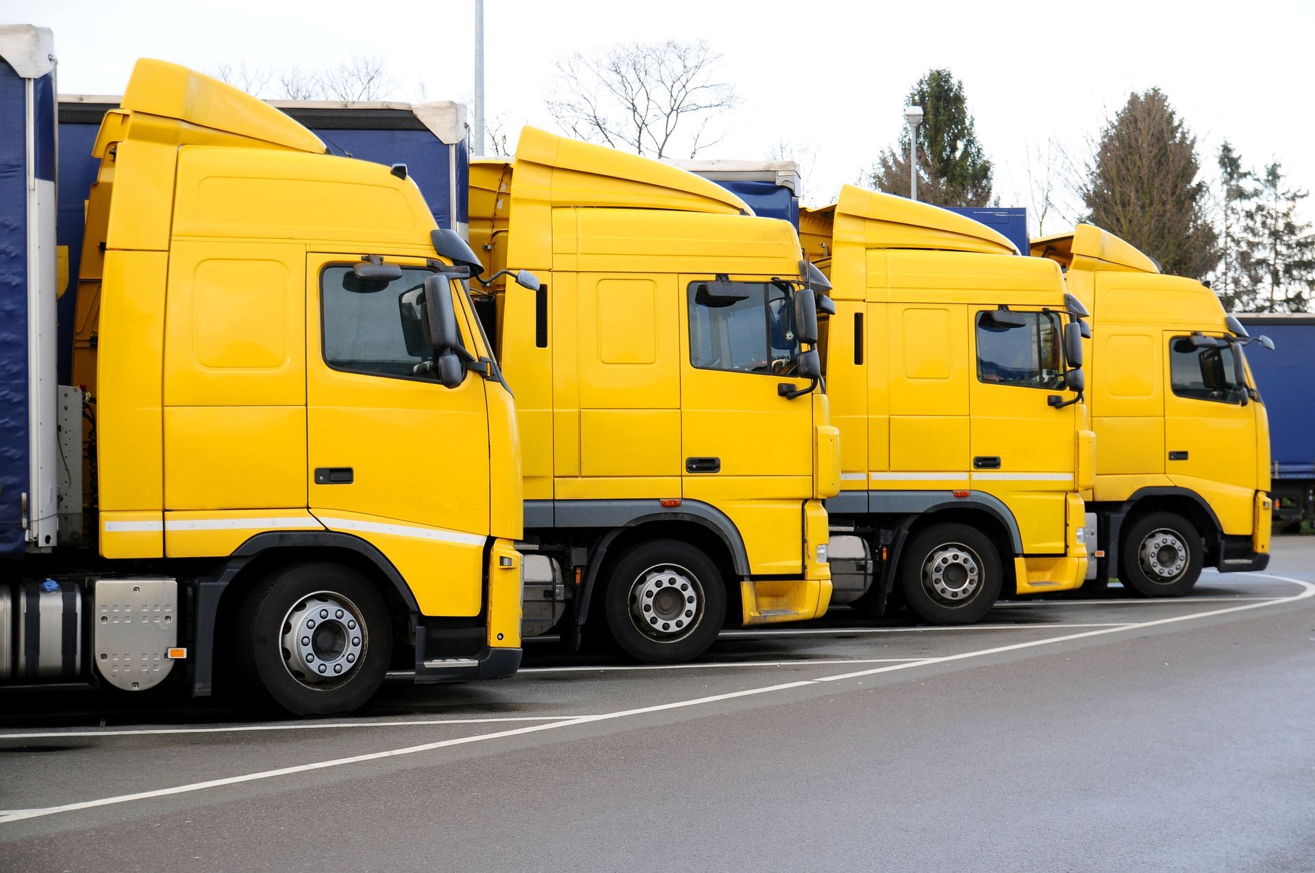 Una fila de camiones semirremolques amarillos están estacionados en un estacionamiento.