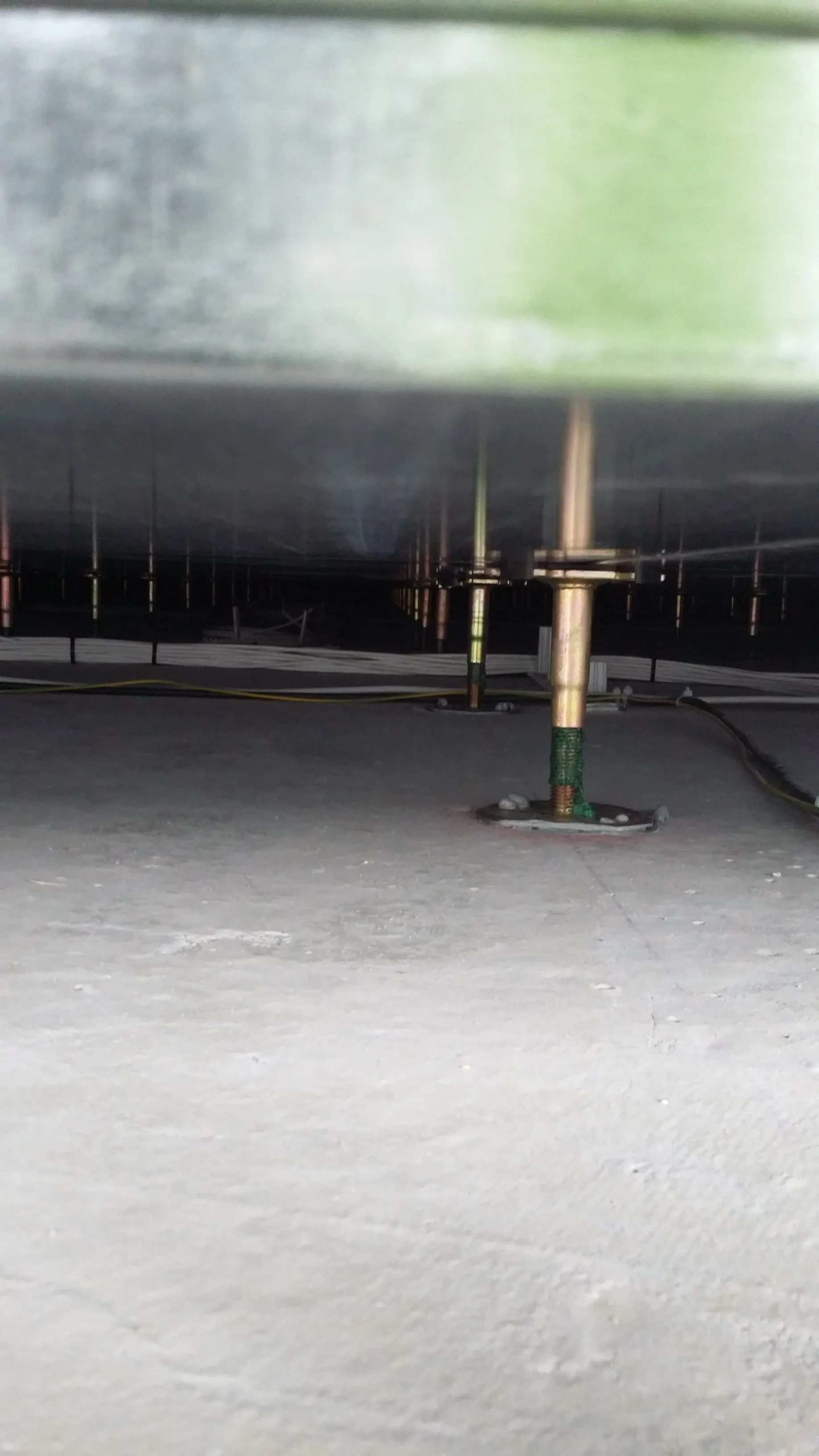 Une structure métallique soutenue par plusieurs poteaux verticaux au-dessus d'une surface grise.