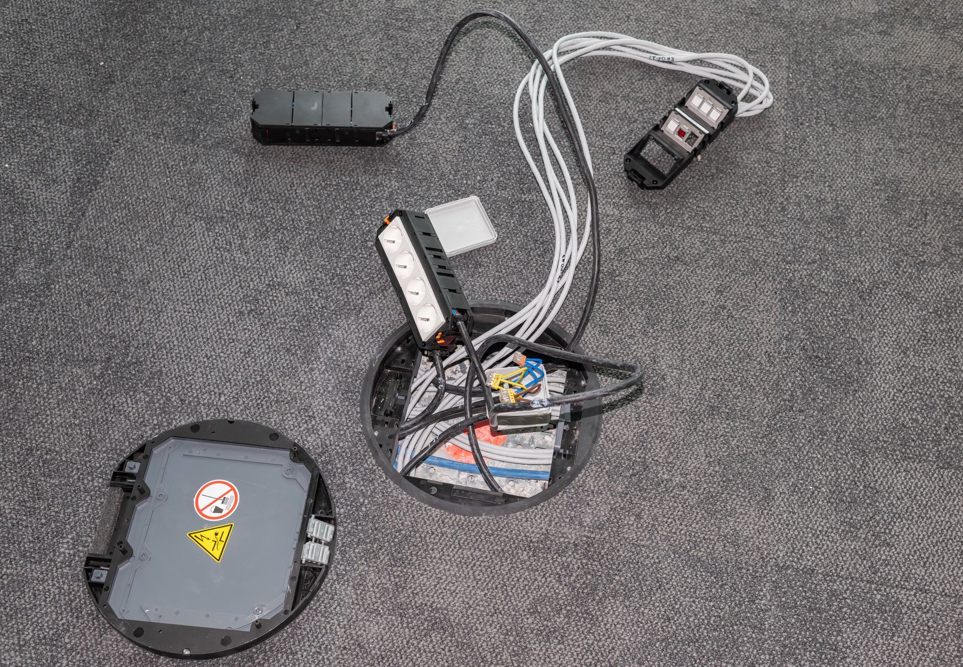 Vue de dessus d'un appareil électronique démonté, avec batterie, fils et circuit imprimé sur une surface grise.