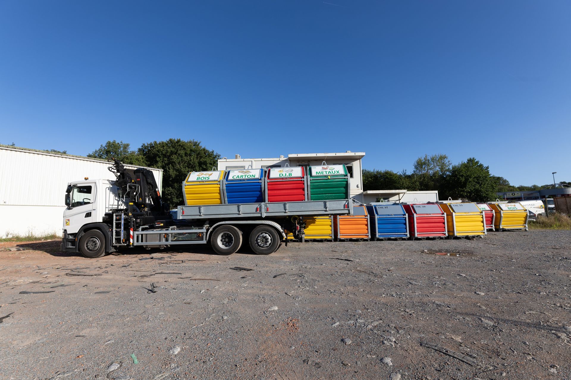 Un camion-plateau déchargeant des conteneurs de tri des déchets.