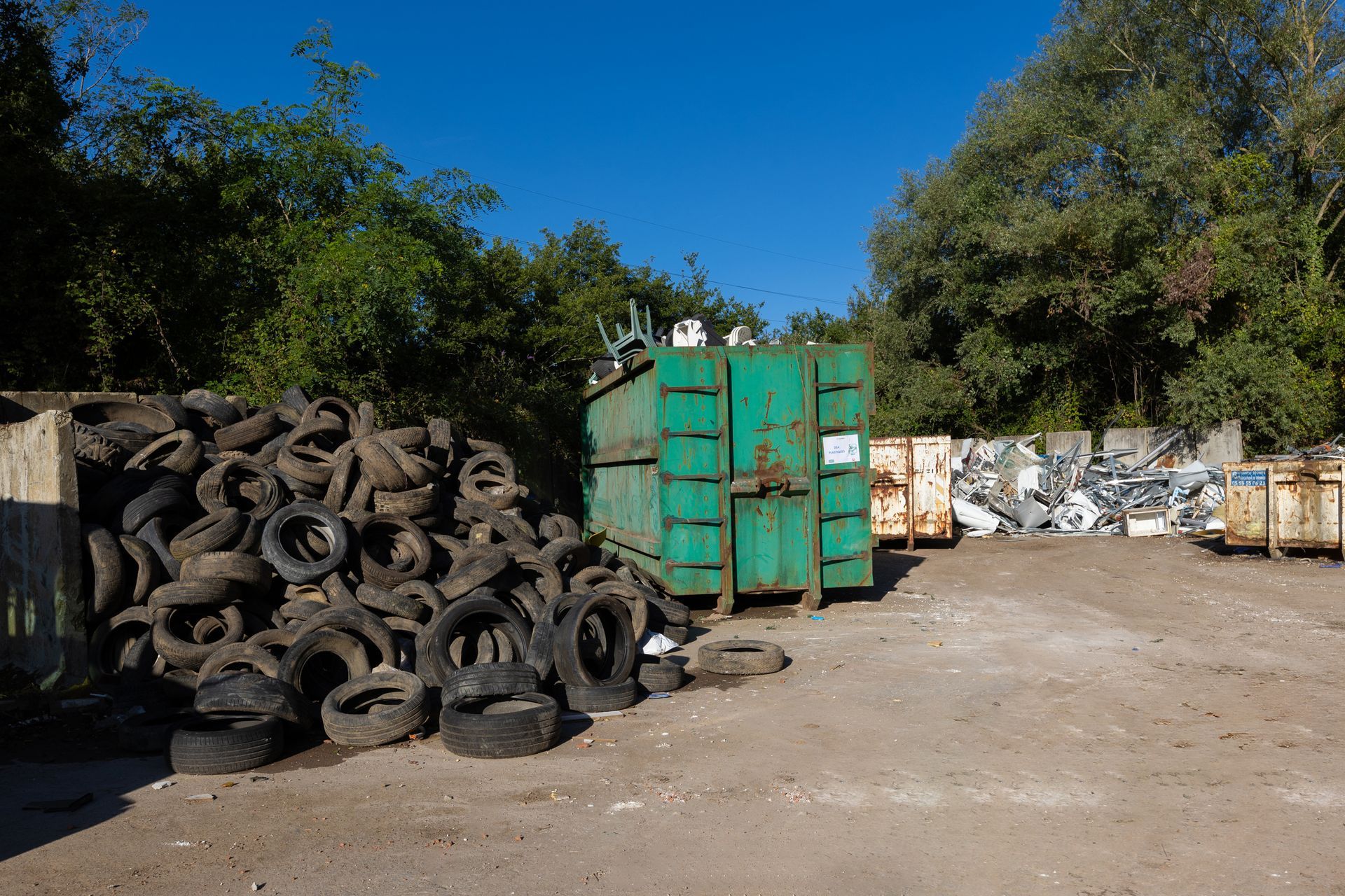 Un conteneur vert et différentes zones d'entrepôt des déchets chez CETRAID.