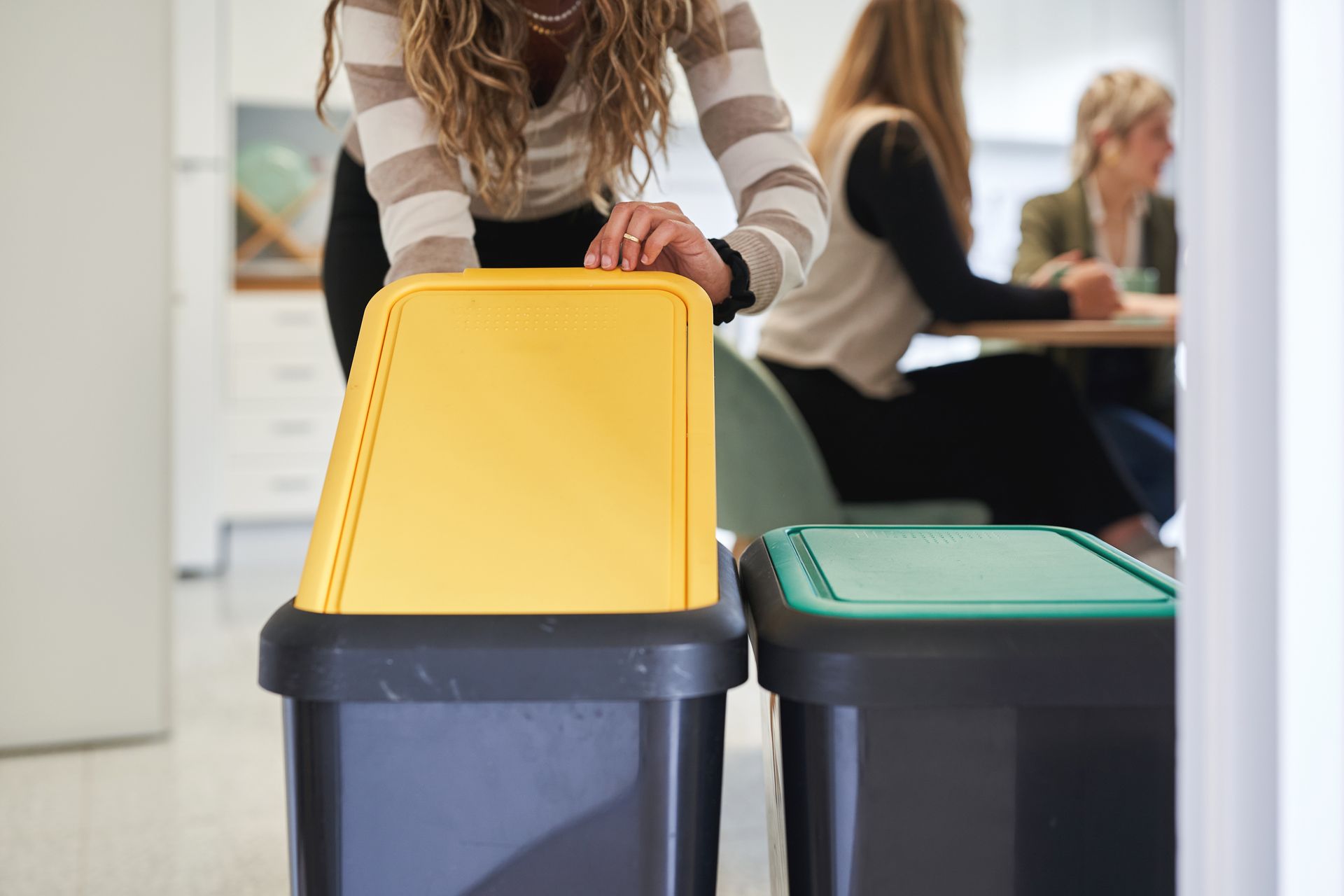 Une femme déposant des déchets dans une poubelle de tri en entreprise.