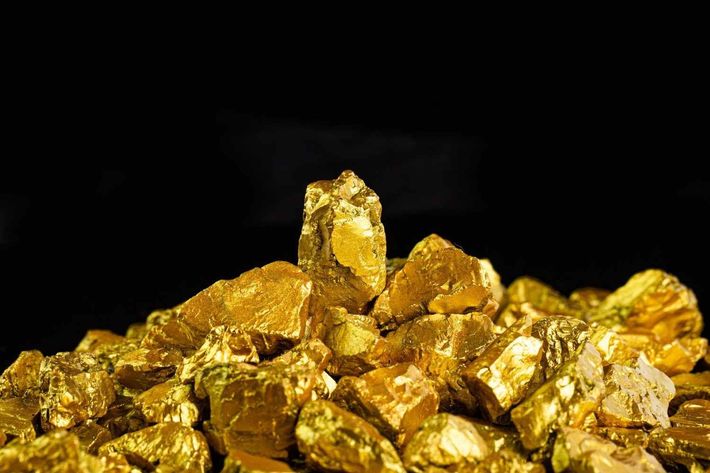 Montón de pepitas de oro brillantes sobre un fondo negro.