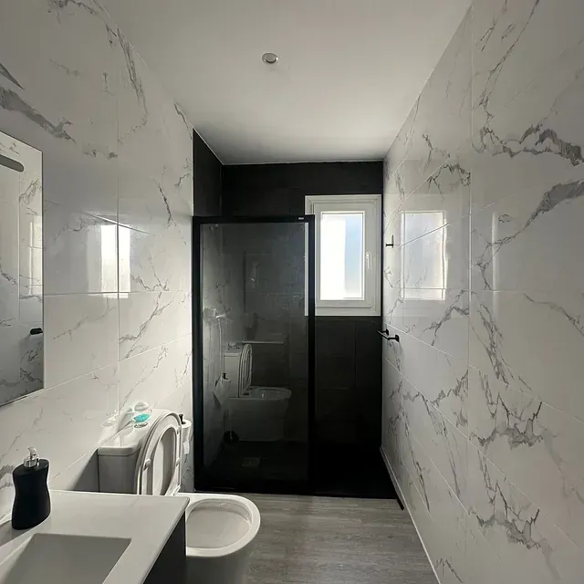 Un baño con inodoro, lavabo, espejo y ducha.