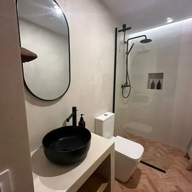 Un baño con inodoro, lavabo, espejo y ducha.