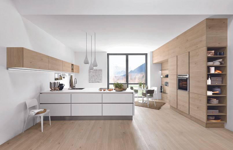 Présentation de la cuisine blanche et meubles couleur bois dans un espace très éclairé devant une grande fenêtre.