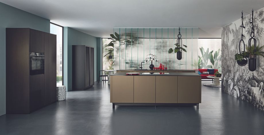 Présentation de l'îlot central de la cuisine dans un espace éclairé avec une verrière à l'arrière.