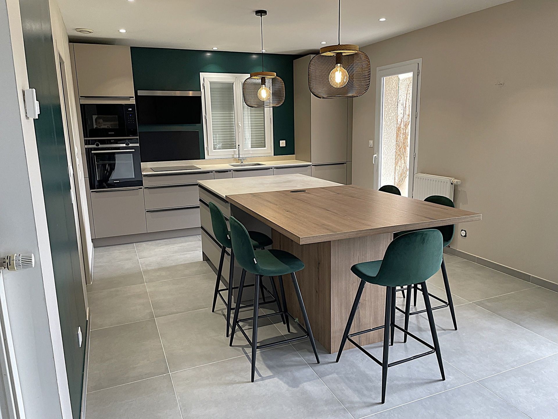 Réalisation d'une cuisine en angle avec électroménager intégré. Couleur vert sapin et beige. Table et îlot central.