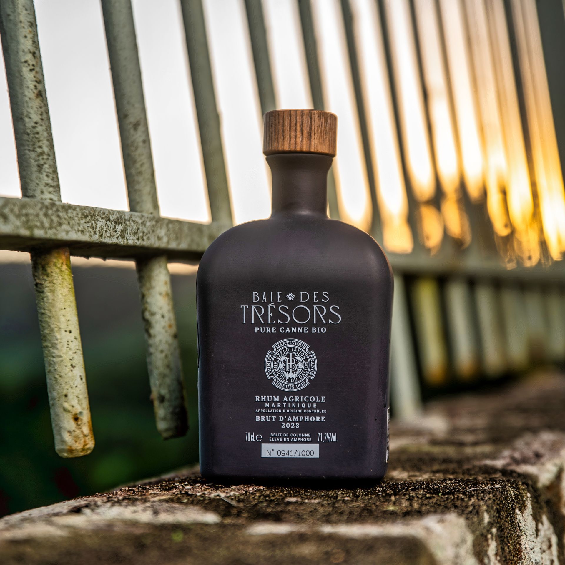 Bouteille de rhum carrée et marron devant une clôture