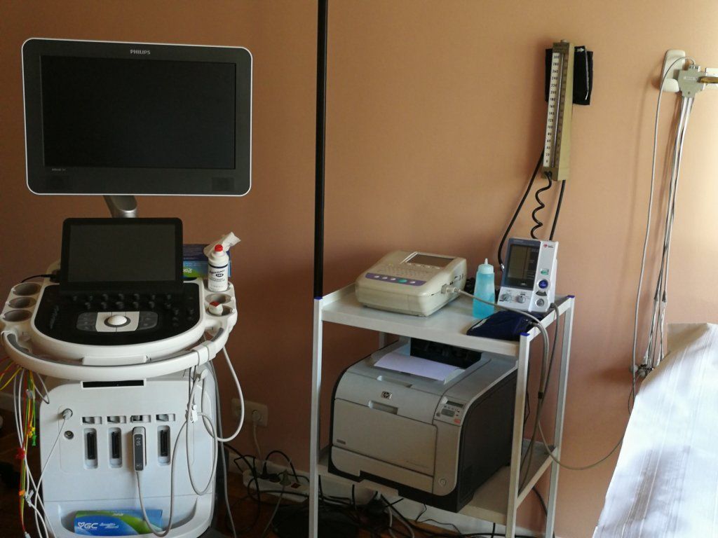 Una máquina de ultrasonido está en una habitación al lado de una impresora.