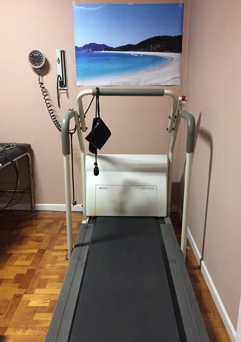 Una cinta de correr en una habitación con una imagen de una playa en la pared.