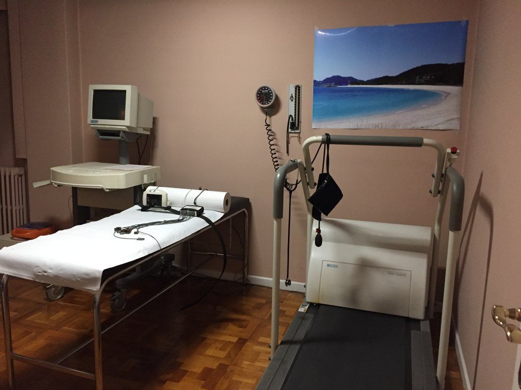 Un consultorio médico con una cinta de correr y una cama.