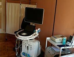 Una máquina de ultrasonido está sobre un carrito en una habitación de hospital.