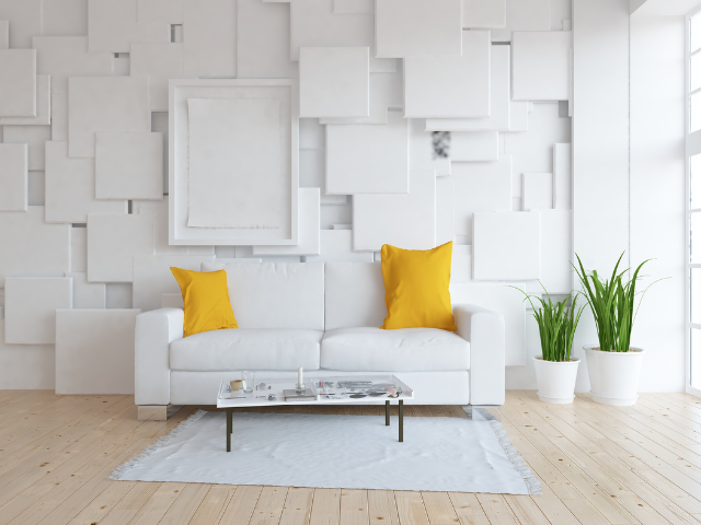 Salon blanc avec canapé blanc, coussins jaunes, œuvres d'art, plantes et parquet.