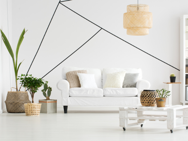Salon blanc avec canapé, plantes et art mural géométrique.