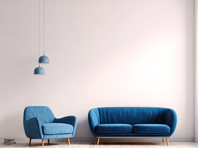 Canapé et fauteuil bleus contre un mur blanc, avec des lumières bleues suspendues.