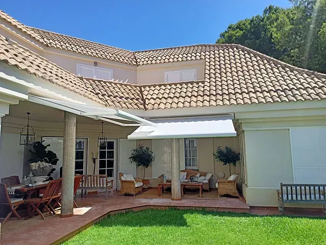 Una casa grande con un toldo blanco al costado.