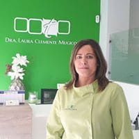 Una mujer con un abrigo verde está parada frente a una pared verde.