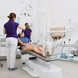 Una mujer está acostada en una silla dental en un consultorio dental.