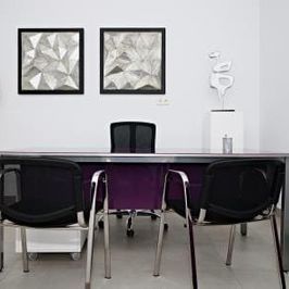 Un comedor con una mesa morada y sillas negras.