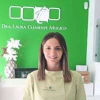 Una mujer está parada frente a una pared verde en un consultorio dental.