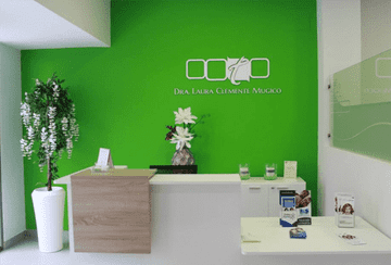Un área de recepción con una pared verde y un escritorio blanco.