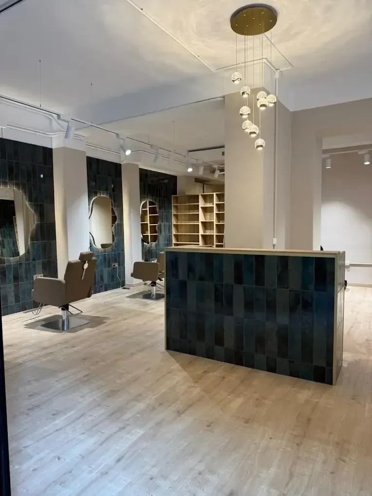 Salón moderno vacío con suelos de mármol, lámparas colgantes y un mostrador de recepción de cuadros oscuros.