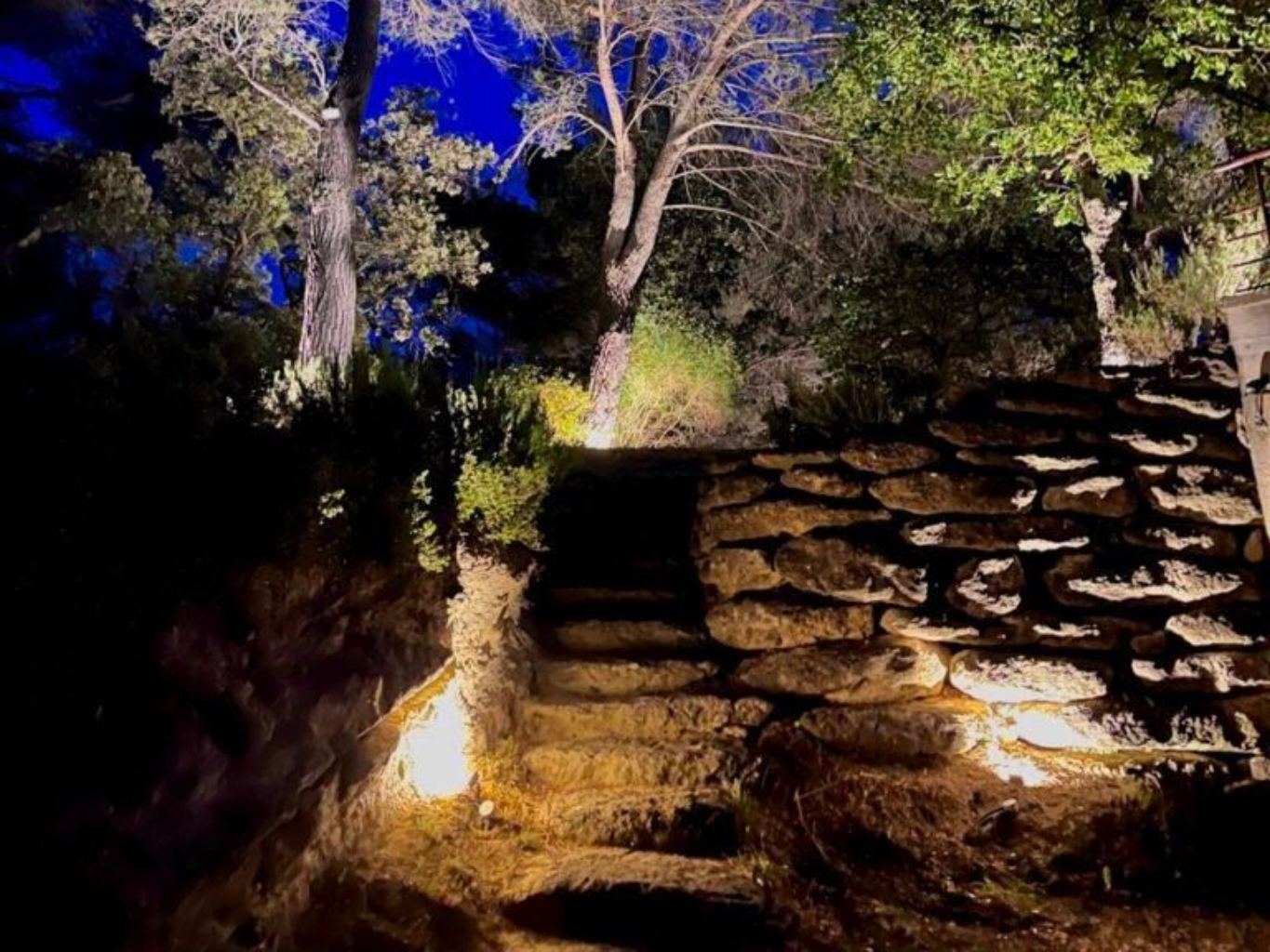Des marches et un mur en pierre, éclairés par des projecteurs la nuit.