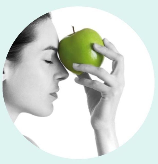 Una mujer oliendo una manzana verde con los ojos cerrados