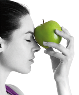 Una mujer sostiene una manzana verde en su cara.