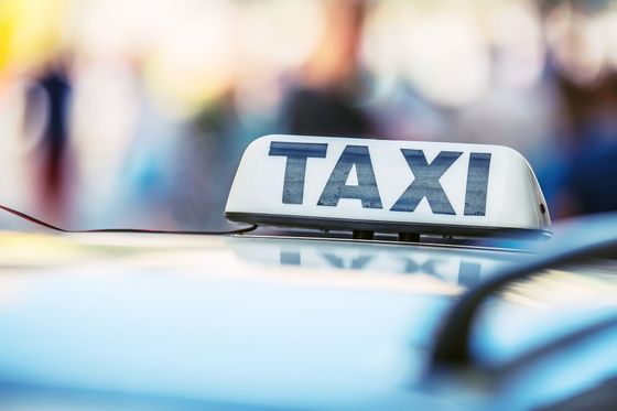 Panneau de taxi sur le toit d'une voiture, lumières de la ville floues en arrière-plan.