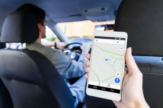 Un passager tient un smartphone affichant la navigation en voiture.
