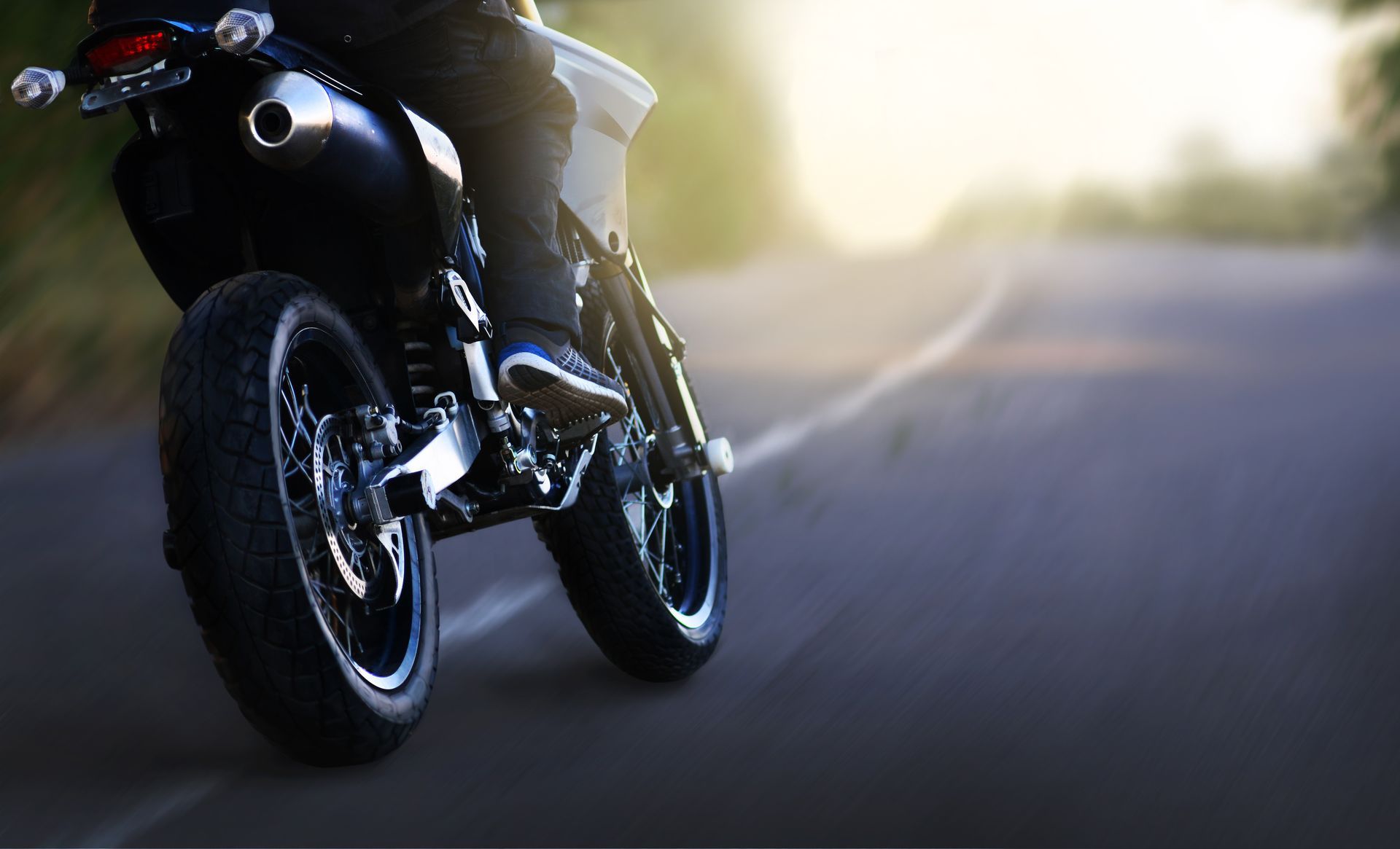 Moto roulant à vive allure sur une route floue au coucher du soleil.