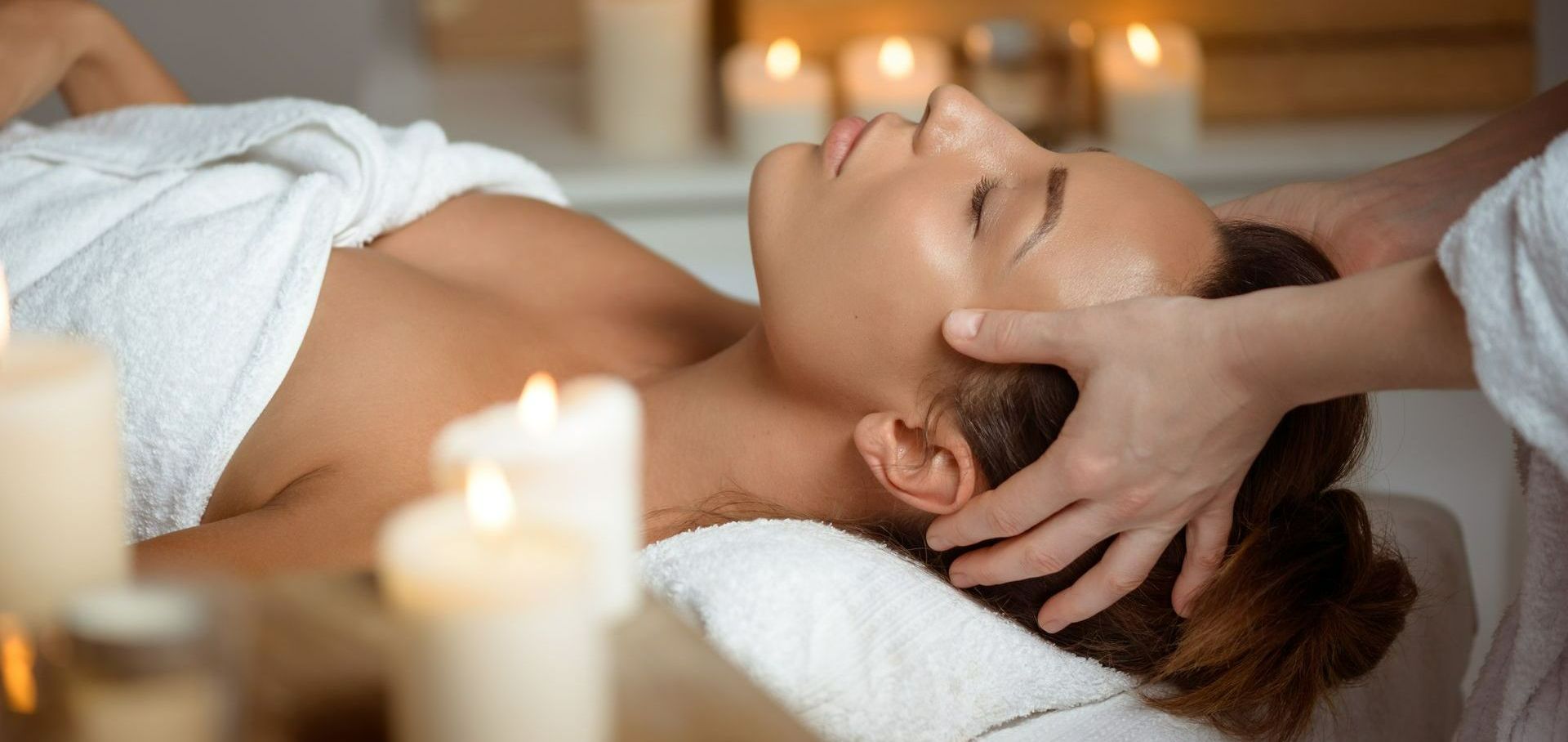 Les mains d'une esthéticienne qui masse une jeune femme.