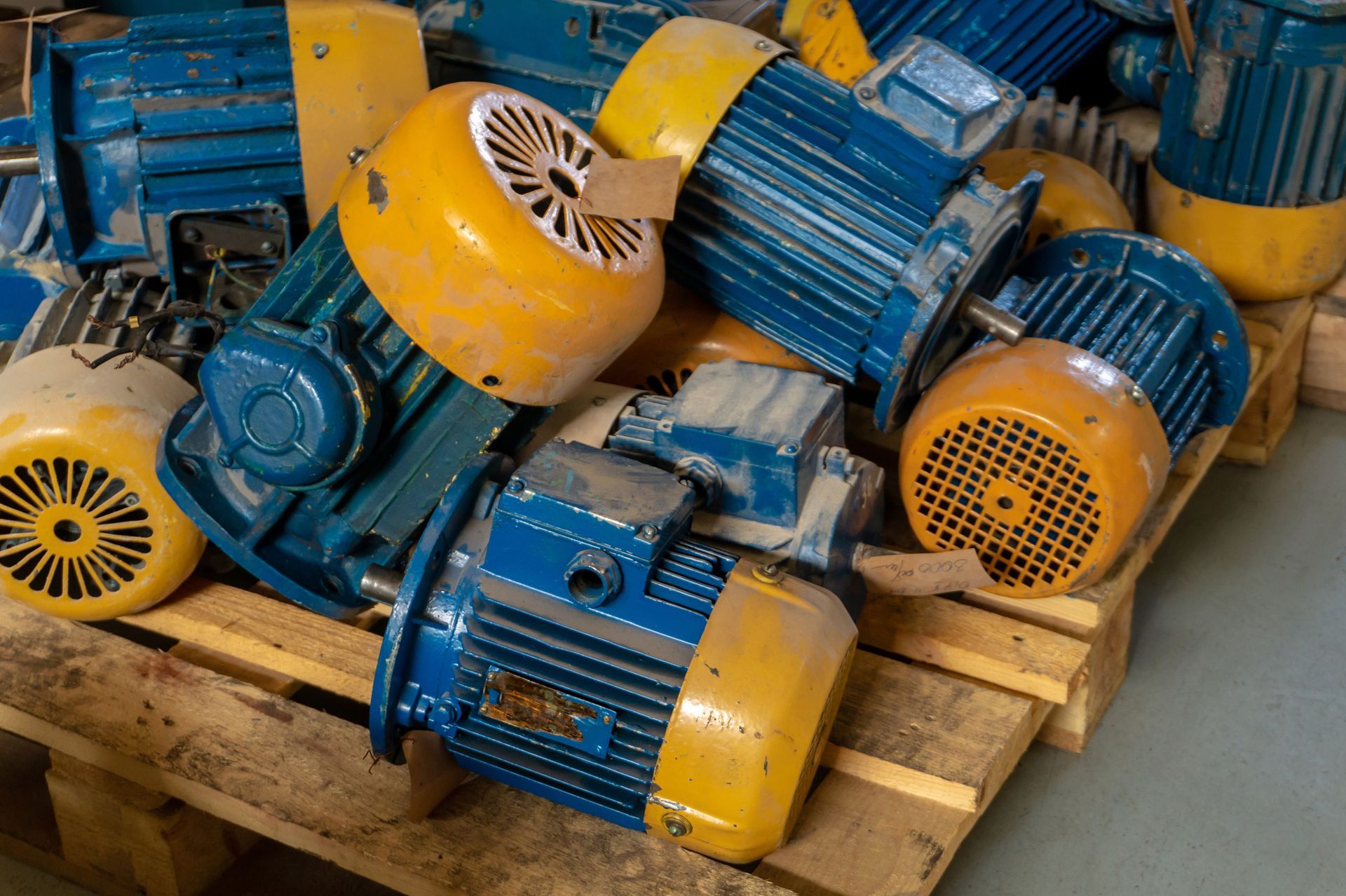 Pila de motores eléctricos azules y amarillos sobre un palé de madera.