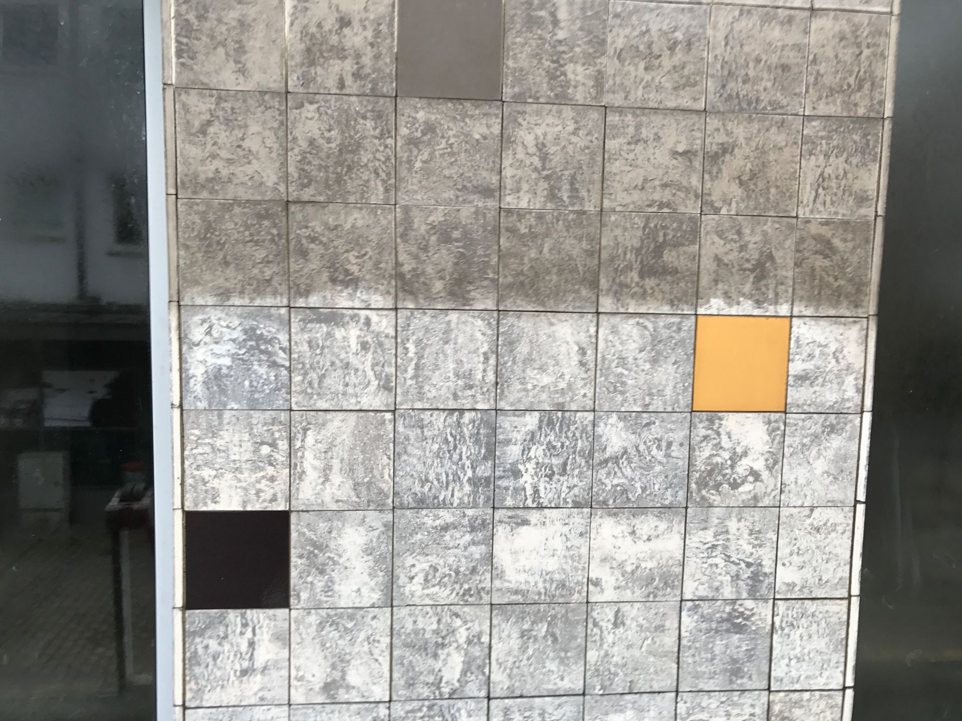 Mosaikfassade eines Gebäudes, welche zur Hälfte gereinigt wurde.
