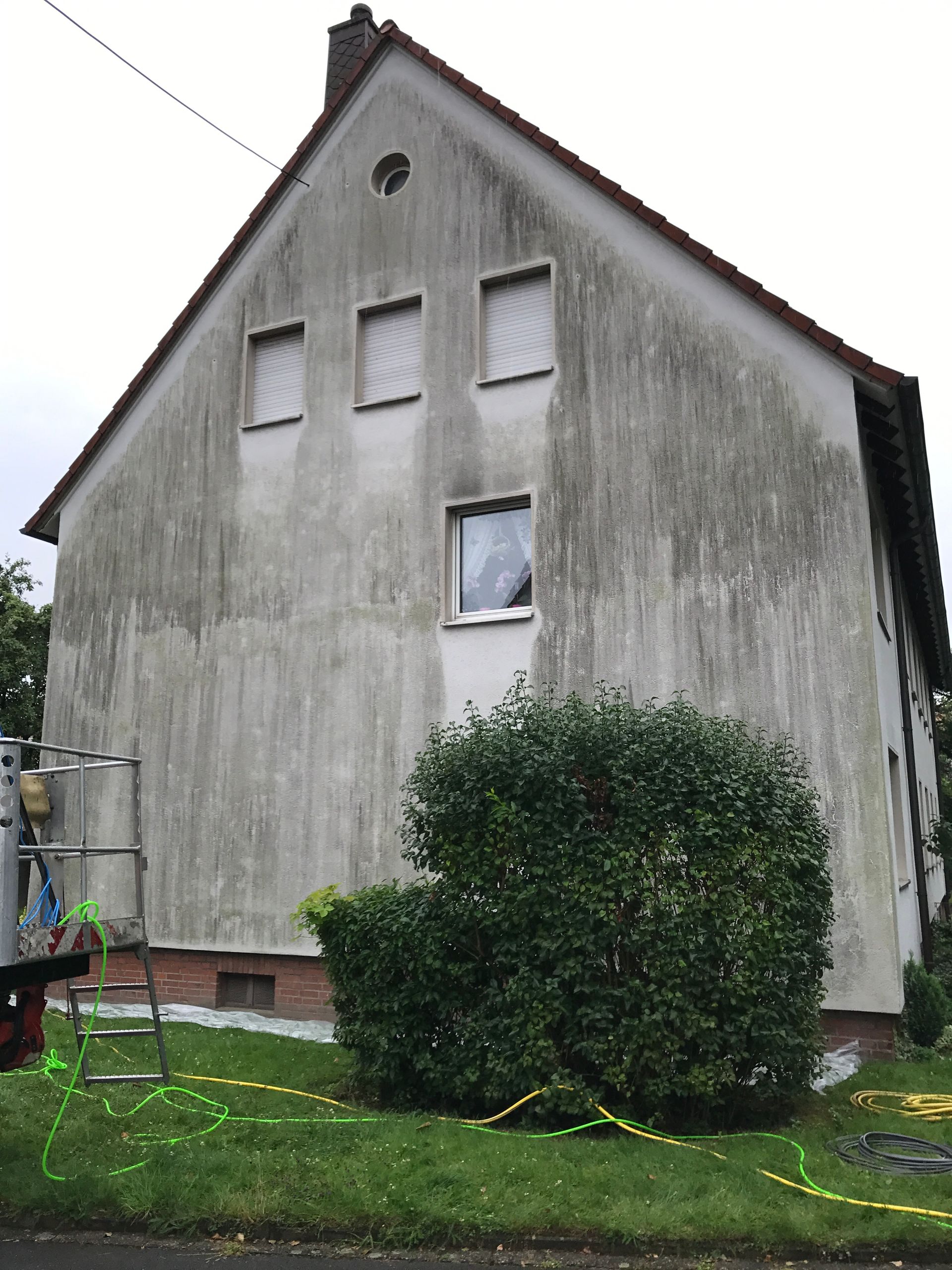 schmutzige Fassade eines weißen Wohnhauses.