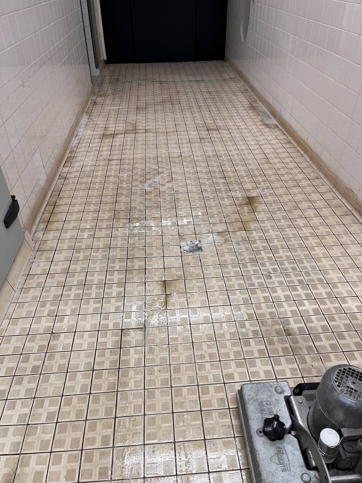 Eine Maschine reinigt einen gefliesten Boden in einem Flur.