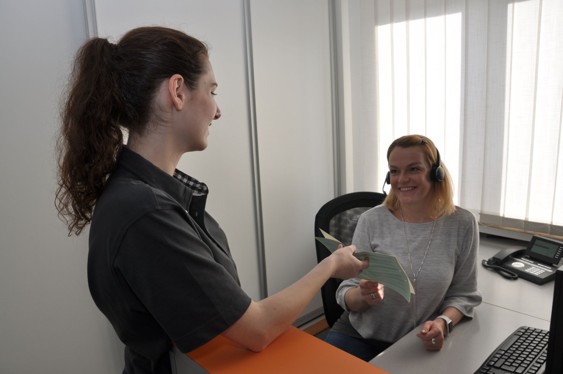 Zwei Frauen sitzen an einem Schreibtisch und unterhalten sich.